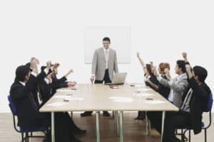 Team Development -Group of business executives raising their hands at a presentation